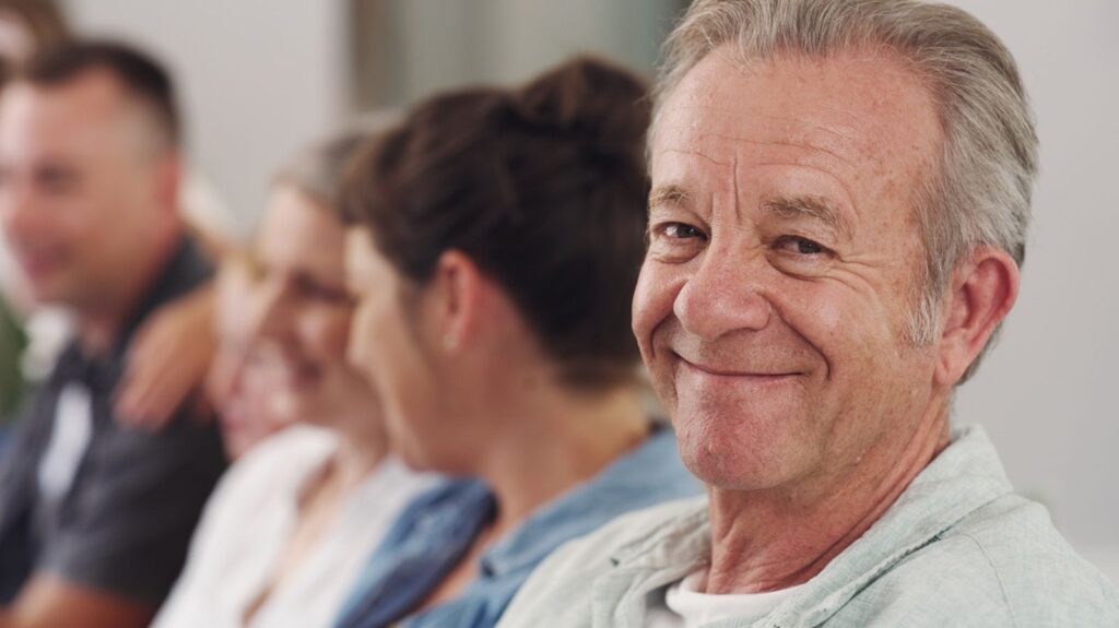 A Retirement Guide for Solo Agers An older man sits in a group staring out at the camera.