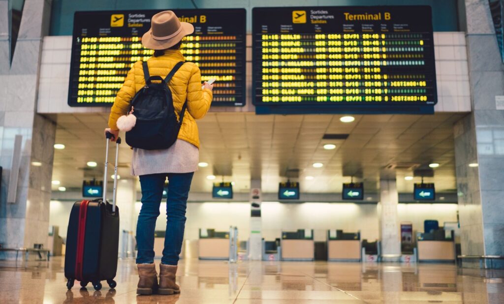 Four Big Airport Rule Changes for Flyers Young woman at the airport in Barcelona checking for the flight schedule
